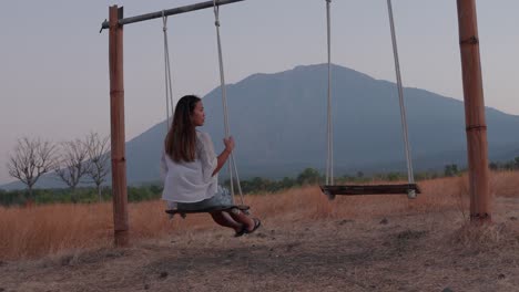 a woman enjoys a peaceful swing ride in front of a breathtaking mountain backdrop