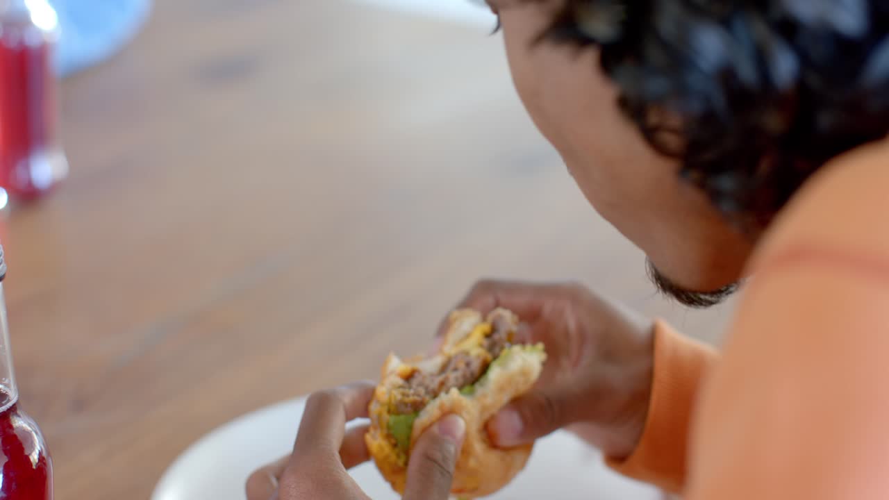 On clip start man is lifting beef burger and biting before inspecting layers and preparing bite