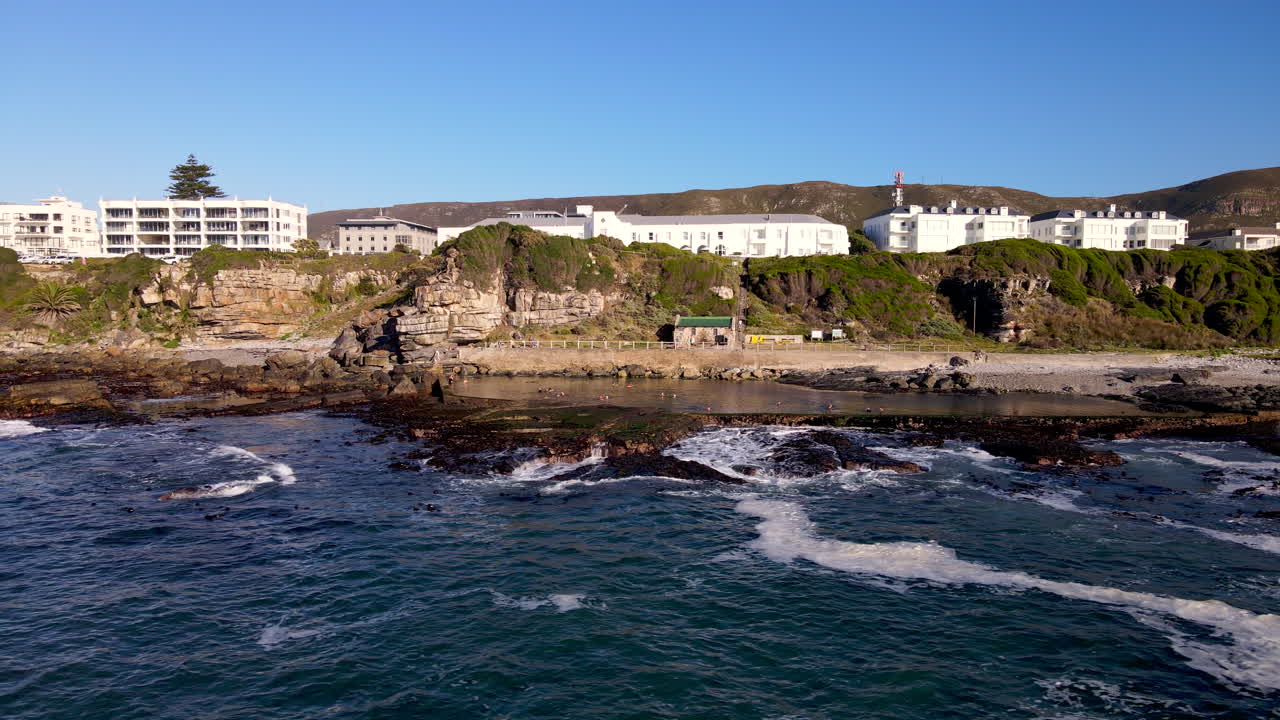 aérea sobre el océano con vista de la piscina de mareas marinas en la costa escarpada, hermanus