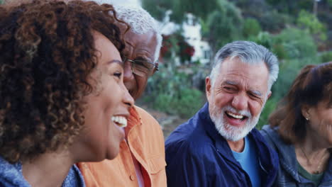 group of senior friends on hike in countryside talking and laughing together