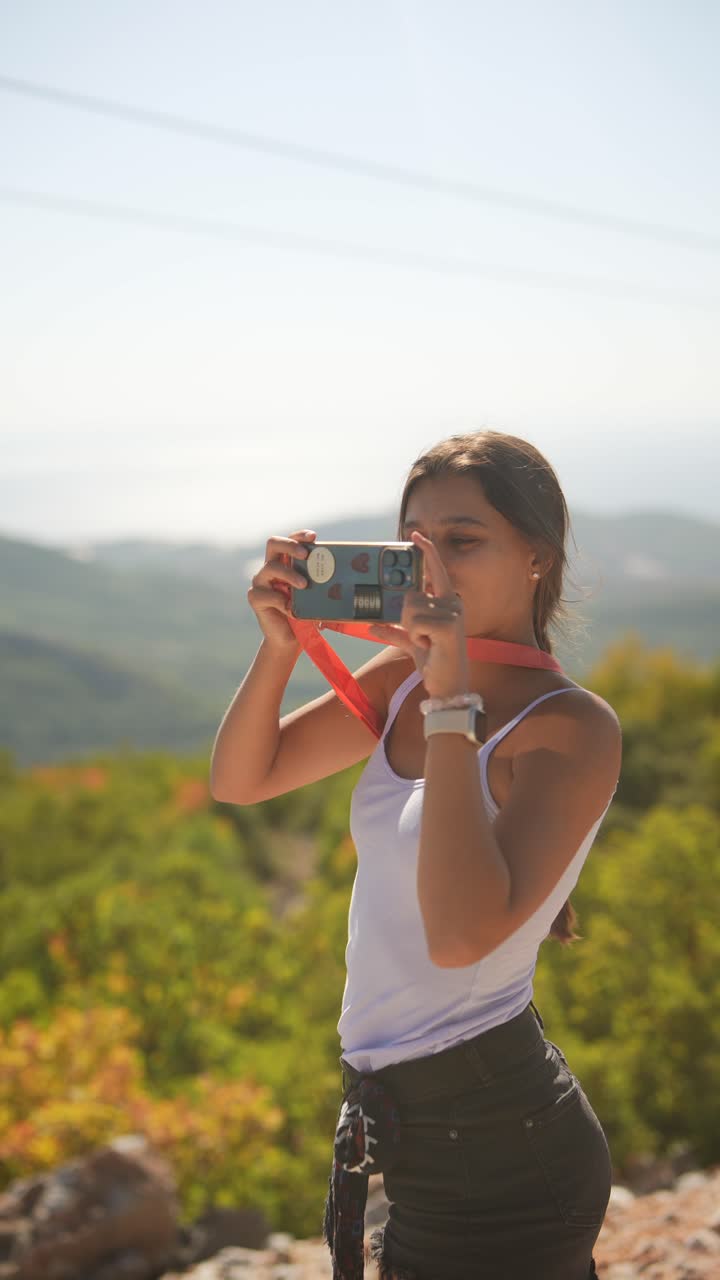 chica adolescente tomando fotos en las montañas