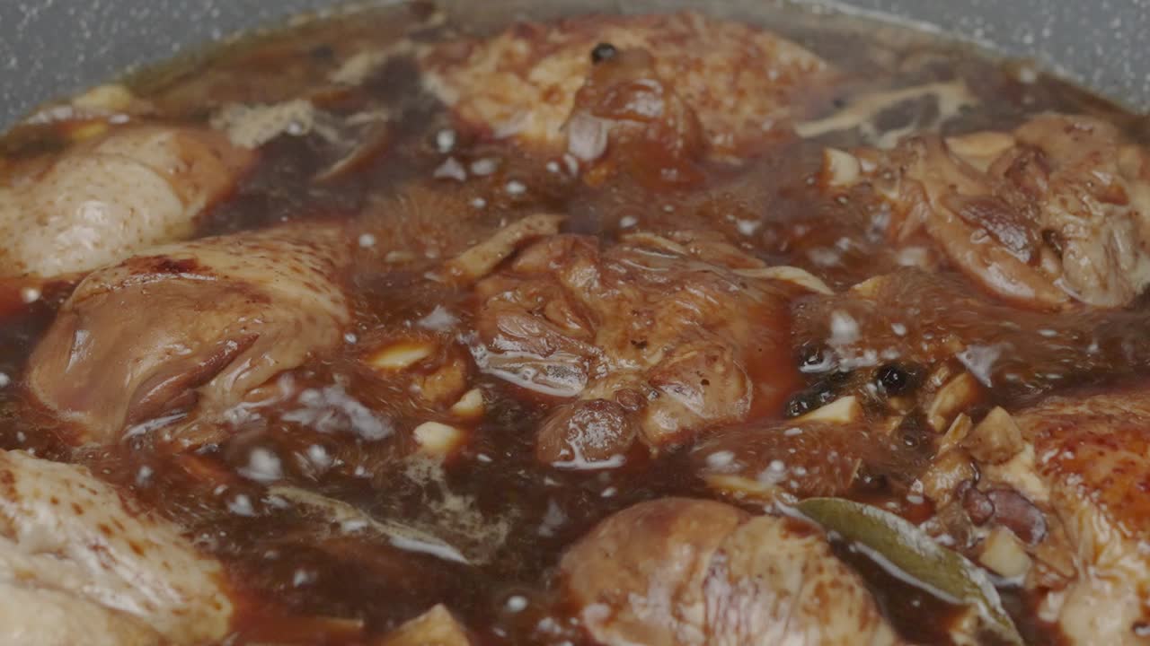 disparo de cerca de muslos de pollo y patas de pollo hirviendo en caldo oscuro