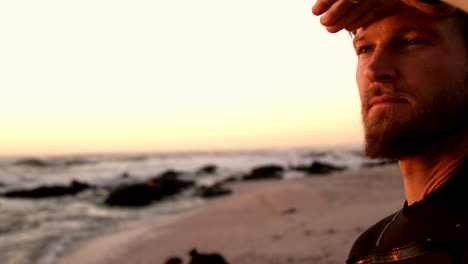 surfista masculino protegiendo los ojos en la playa 4k