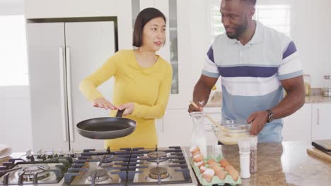 Happy-diverse-couple-cooking-and-preparing-breakfast-in-kitchen