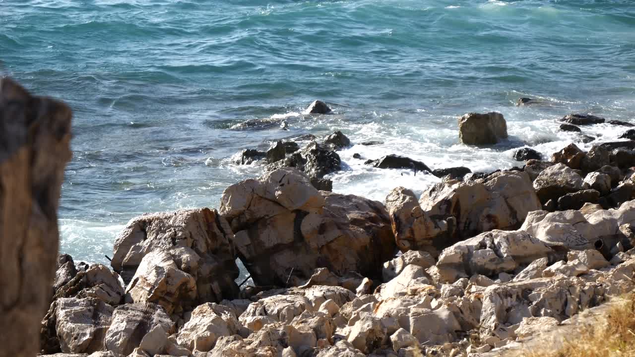 Skummende bølger fra Adriaterhavet slår mod den klippefyldte kyst på en albansk strand.