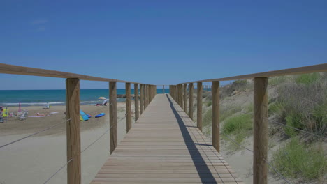 wooden walkway path by sandy beach on spanish mediterranean coastline