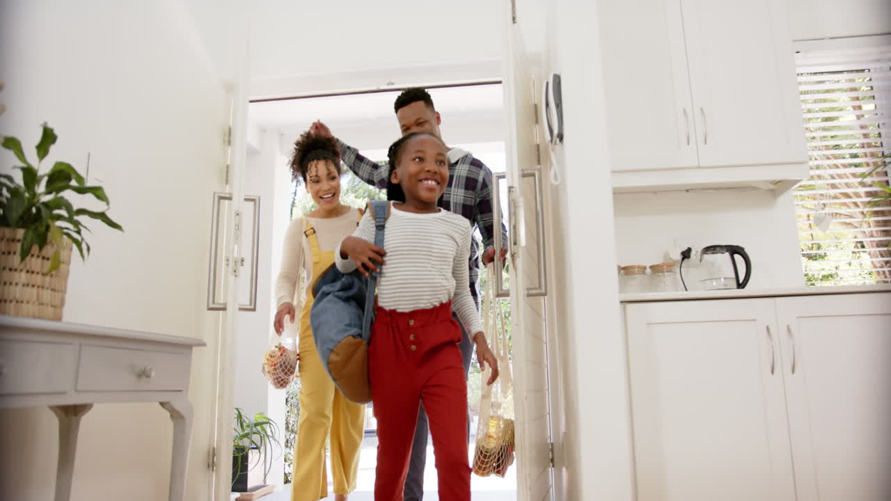 Happy african american parents and daughter coming home from school, slow motion