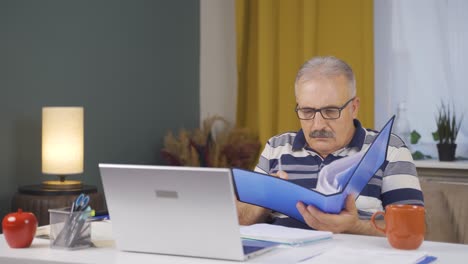 Home-office-worker-old-man-looking-at-the-file-angrily.