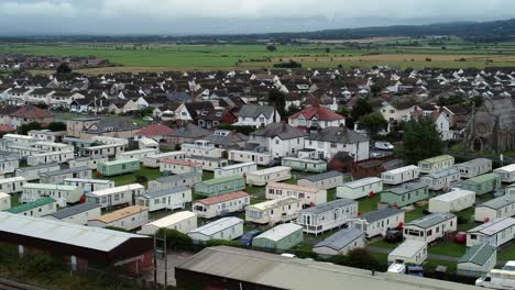 Static-caravan-trailer-beachfront-staycation-holiday-home-campground-resort-aerial-view-drift-left-low