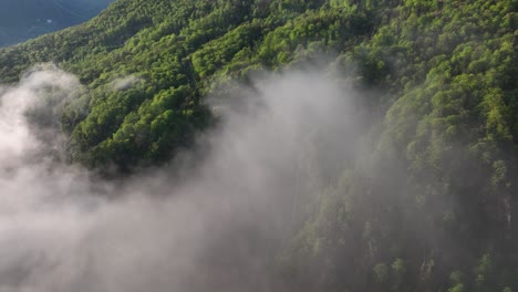vuelo a través de nubes grises a lo largo de la empinada ladera de los alpes italianos