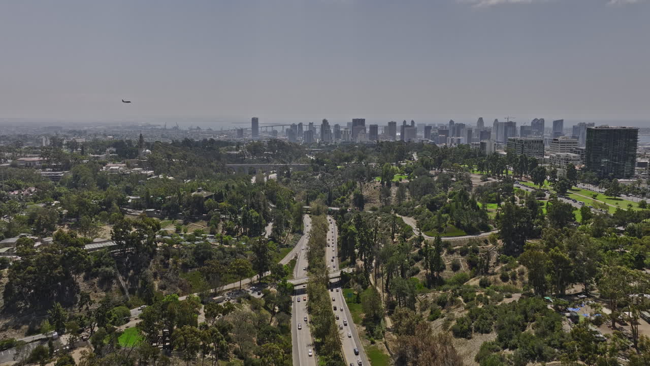샌디에고 캘리포니아 공중 v75 비행 발보아 공원은 카브릴로 고속도로 위의 다리와 시내 도시 경관을 캡처하는 비행기로 하늘을 가로질러 날아갑니다 - 매빅 3 시네로 촬영 - 2022년 9월