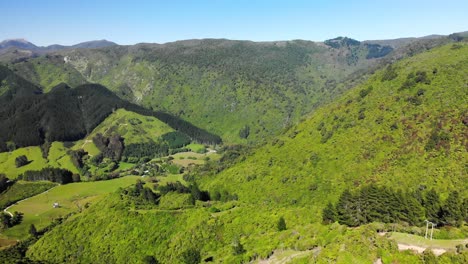 Aerial-landscape-view-of-Takaka-hill-valley,-covered-in-bright-green-and-lush-vegetation,-New-Zealand,-on-a-sunny-day