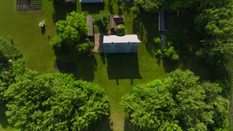 top-down-drone-shot-of-a-large-farm-with-multiple-barn-structures-and-out-buildings-on-a-sunny-day