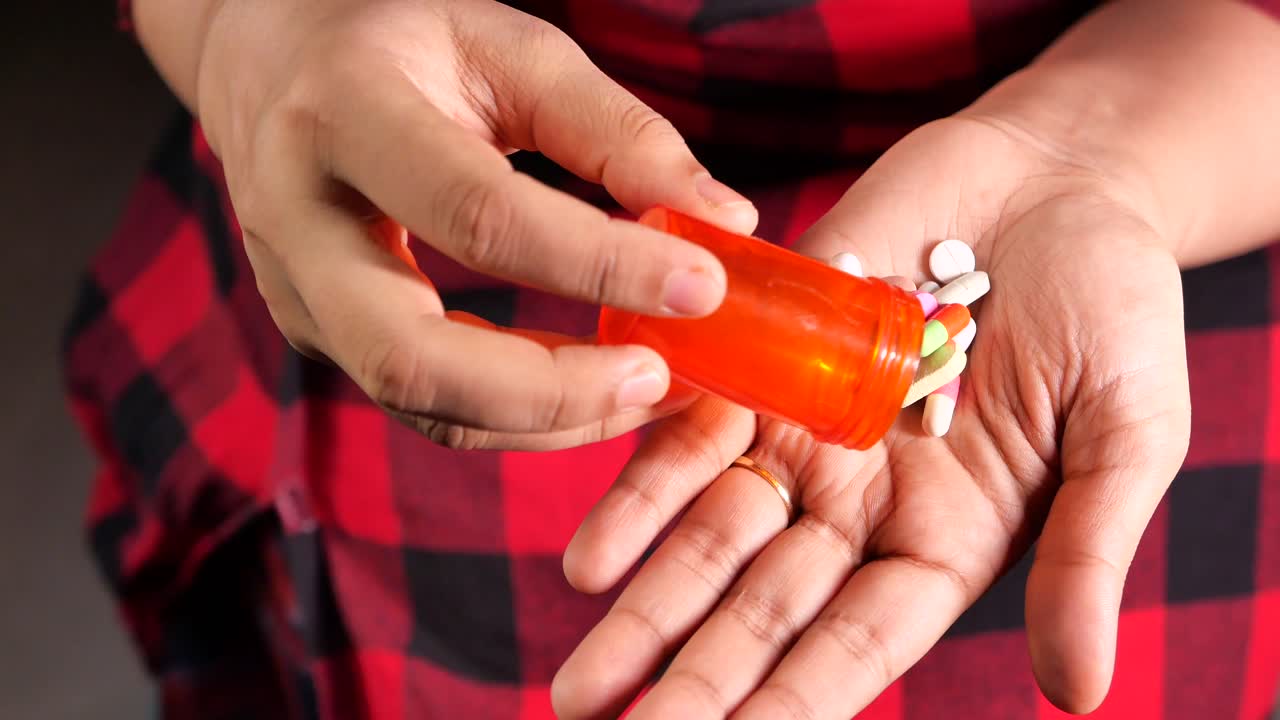 여자 는 오렌지색 병 에서 약 을 손 에 고 있다