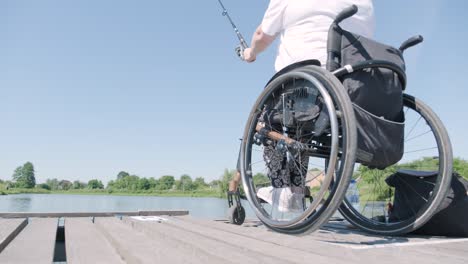 man with disabilities fishing at a lake. wheelchair. summertime. disabled person fishing