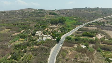 a wide aerial shot from a drone captures a rural landscape with expansive farmlands, crisscrossed by roads and bordered by natural vegetation