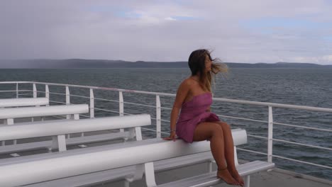 young woman sitting on deck of ferry admiring the ocean - ferry trip to north stradbroke island, australia