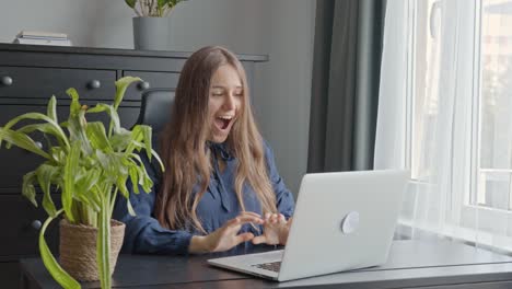 Thrilled-excited-young-woman-receiving-amazing-news-working-on-laptop-at-office