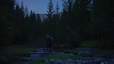 Un-Ciclista-Cruza-Un-Pequeño-Puente-De-Arroyo-Por-La-Noche