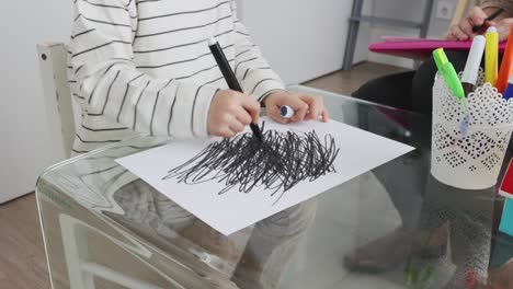 Unrecognizable kid drawing black strokes