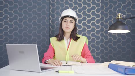 the woman engineer looks at the camera and makes a stop sign.