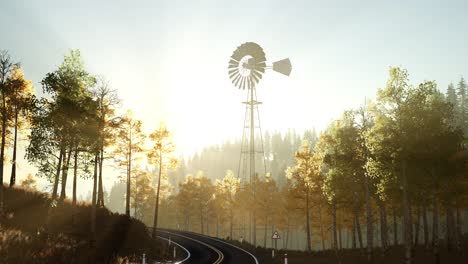 typical old windmill turbine in forest at sunset