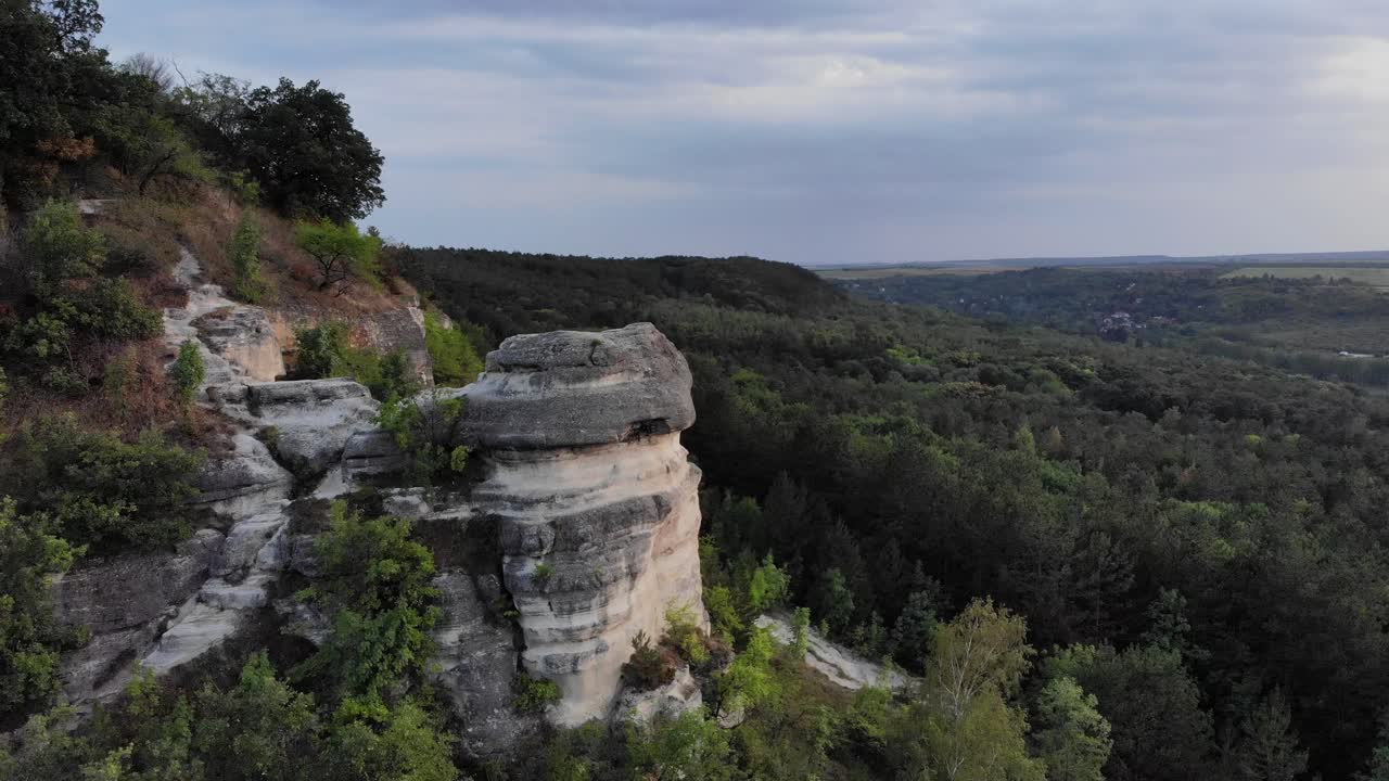 dron aéreo lento y épico orbita alrededor de una roca sólida interesante en la hora del atardecer con un hermoso entorno forestal