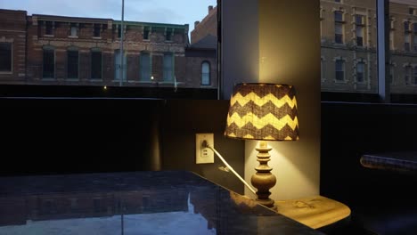 Lamp-on-a-table-in-a-room-with-windows-on-buildings