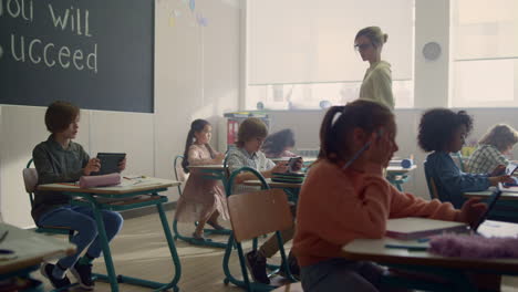 Young-schoolteacher-talking-with-pupils.-Teacher-explaining-lesson-to-students