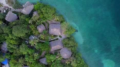 accommodation in thatched-roof huts overlooking the turquoise sea on a tropical island