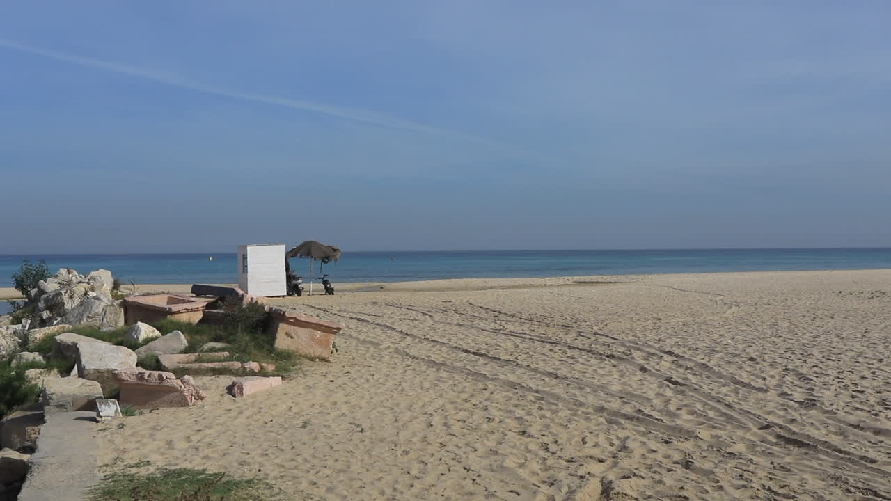 una escena de playa pacífica con una pequeña ensenada y una vista distante del océano en una antigua ciudad árabe