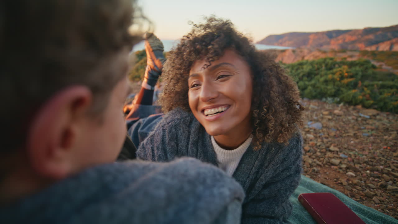 Happy sweethearts relaxing evening beach closeup. Curly woman lying on blanket