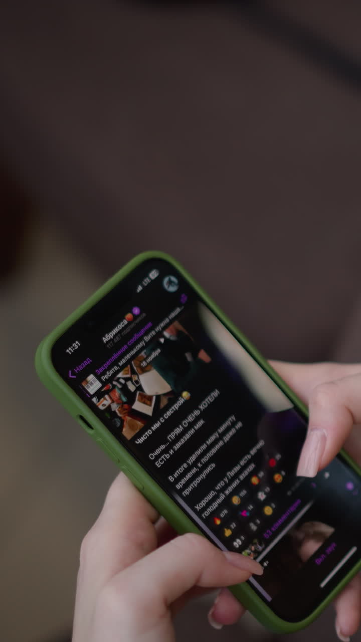 Close-up rear view of young lady seated in modern mall with phone in her hand, scrolling through it, soft focus on screen displaying content, subtle background of urban setting through glass