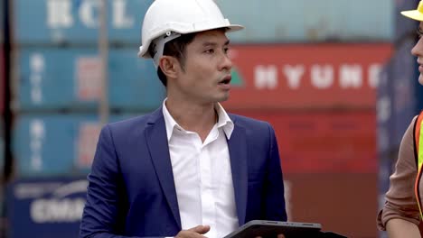 businessman and employee woman worker in safety dress and hat working at cargo warehouse, walking in logistics center factory to check outdoor warehouse cargo container ship.