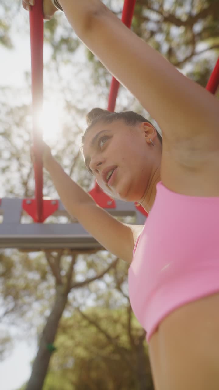 Woman doing pull-ups on monkey bars during an outdoor workout
