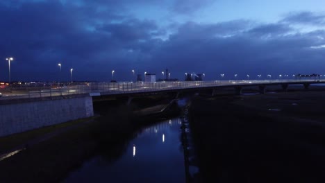 Aerial-rising-view-modern-illuminated-quiet-highway-lanes-road-intersection-traffic-over-canal