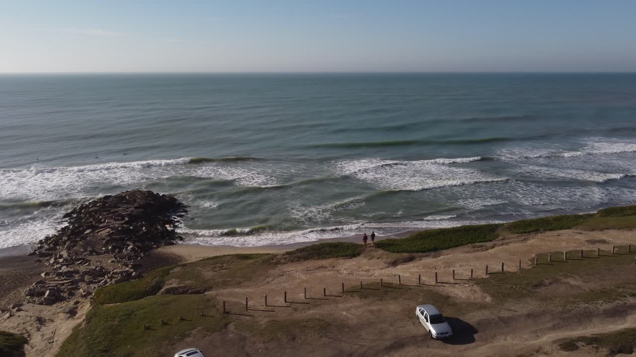 dos amigos de pie y mirando las olas del océano atlántico, playa chapadmalal en mar del plata en argentina