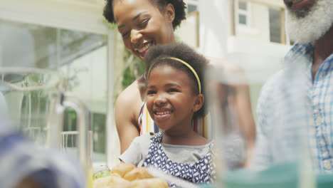 Happy-african-american-family-talking-and-having-breakfast-in-garden