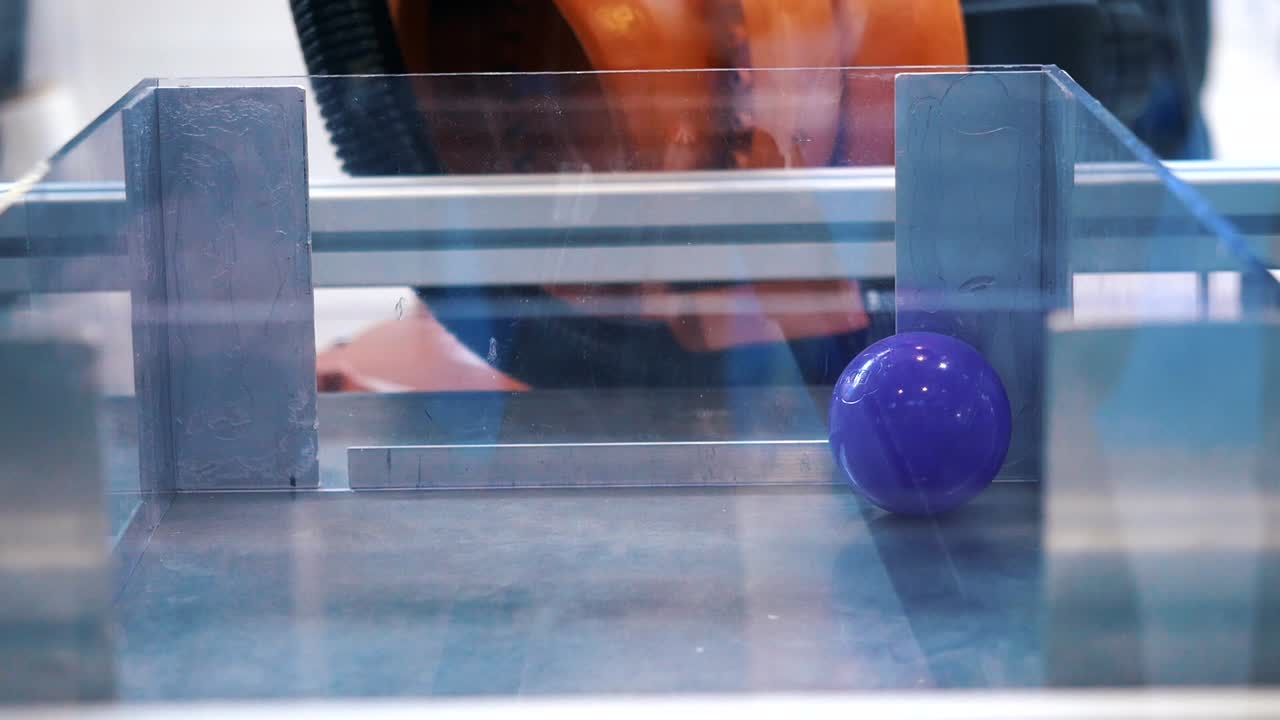 robot manipulando una esfera dentro de un recipiente transparente