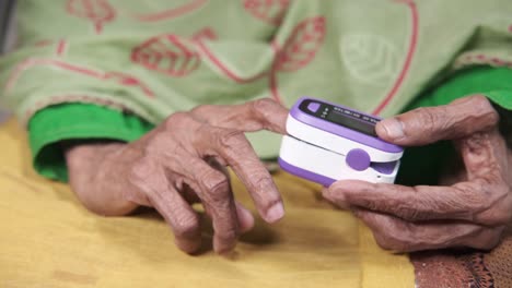 persona de edad avanzada que utiliza un oxímetro de pulso
