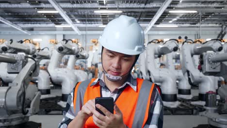 trabajador de una fábrica usando un teléfono inteligente cerca de robots