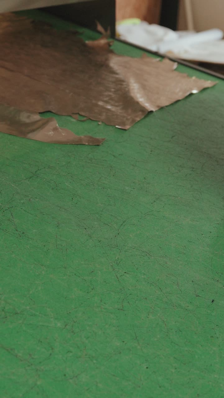 신발 공장에서 작업자가 분류된 가죽 재단 조각을 롤링하는 수직 뷰