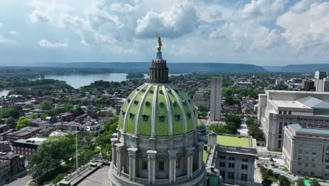 aerial orbit of green cupola of pennsylvania state capitol building in harrisburg. sunny day with clouds at sky. historic buildings in american town