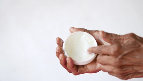 persona de edad avanzada aplicando crema a sus manos