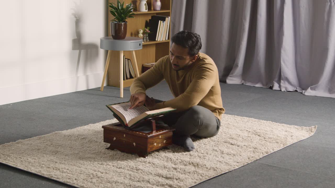 Muslim Man At Home Sitting On Floor And Reciting From The Quran 2