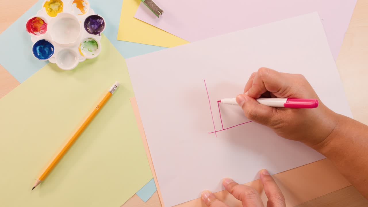 Person draws bar graph with pink pen on white paper, overhead shot, bright lighting