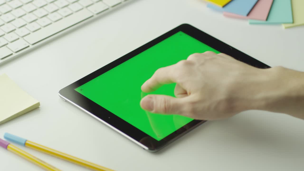 디자이너는 풍경 모드에서 녹색 화면을 가진 태블릿을 사용하고 있습니다.