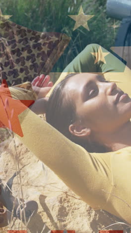 animation of american flag over biracial woman lying in mountains