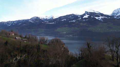 Hovering-above-the-natural-surroundings-of-Seerenbachfälle-in-Weesen-Amden,-Switzerland,-a-serene-lake-nestles-at-the-valley-floor,-embraced-by-snow-capped-mountains-in-the-backdrop