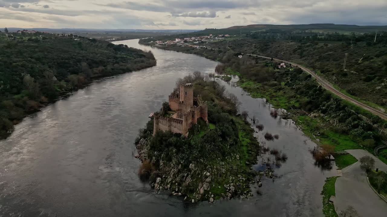 Castelo de Almourol no Rio Tejo, perto de Vila Nova da Barquinha, Portugal, mostrando uma fortaleza medieval em uma ilha rochosa em meio a uma paisagem dramática ao pôr do sol, vista aérea cinematográfica.